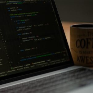 Close-up of a laptop screen with code and a coffee mug, perfect for tech abstract themes.